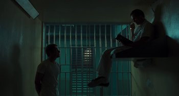 Movie still from “I Love You Phillip Morris” (2009), directed by John Requa – Two men in a jail cell one is sitting on the floor and the other is standing up; Wide shot, Low angle