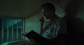 Movie still from “I Love You Phillip Morris” (2009), directed by John Requa – A man sitting in front of a window reading a book; Medium shot, Low angle