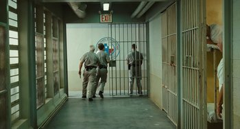 Movie still from “I Love You Phillip Morris” (2009), directed by John Requa – A group of men standing next to each other in front of bars; Wide shot, High angle