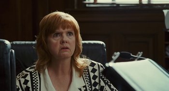 Movie still from “I Love You Phillip Morris” (2009), directed by John Requa – An older woman sitting at a desk in an office setting; Close Up shot, Low angle