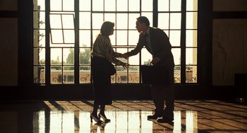 Movie still from “I Love You Phillip Morris” (2009), directed by John Requa – A man and a woman shaking hands in front of a window; Wide shot, Low angle