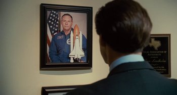 Movie still from “I Love You Phillip Morris” (2009), directed by John Requa – A man in a suit looking at a picture of a man in a space suit; Close Up shot, Over the shoulder angle