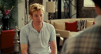 Movie still from “I Love You Phillip Morris” (2009), directed by John Requa – A man sitting in front of another man in a living room; Medium shot, Over the shoulder angle