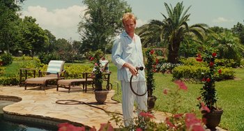 Movie still from “I Love You Phillip Morris” (2009), directed by John Requa – A man holding a tennis racquet on top of a patio; Medium shot, Over the shoulder angle