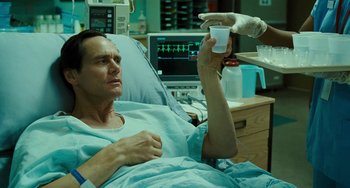 Movie still from “I Love You Phillip Morris” (2009), directed by John Requa – A man in a hospital bed holding up a cup; Medium shot, Low angle