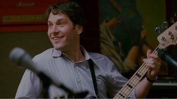 Movie still from “I Love You, Man” (2009), directed by John Hamburg – A man smiles while holding a bass guitar; Close Up shot, Over the shoulder angle