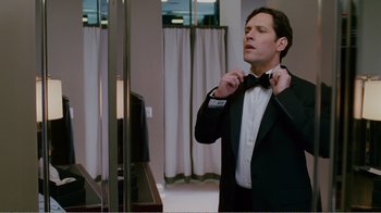 Movie still from “I Love You, Man” (2009), directed by John Hamburg – A man adjusts his bow tie in front of a television; Medium shot, Low angle