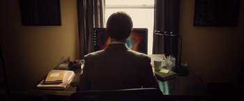 Movie still from “I Origins” (2014), directed by Mike Cahill – A man sitting at a computer in front of a window; Medium shot, High angle