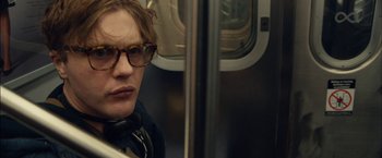 Movie still from “I Origins” (2014), directed by Mike Cahill – A man wearing glasses sitting on a subway train; Close Up shot, Over the shoulder angle