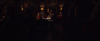 Movie still from “I Origins” (2014), directed by Mike Cahill – A group of people sitting at a table in a dark room; Wide shot, High angle