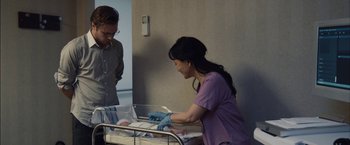 Movie still from “I Origins” (2014), directed by Mike Cahill – A man and a woman standing next to a baby in a crib; Medium shot, Over the shoulder angle