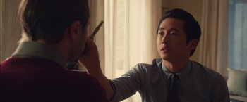 Movie still from “I Origins” (2014), directed by Mike Cahill – A man holding a cigarette in one hand while another holds a cell phone in the other hand; Close Up shot, Over the shoulder angle