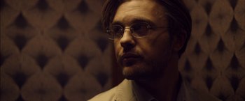 Movie still from “I Origins” (2014), directed by Mike Cahill – A person wearing glasses and a suit; Close Up shot, Low angle