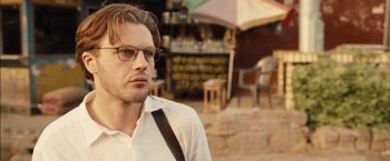 Movie still from “I Origins” (2014), directed by Mike Cahill – A man wearing glasses standing in front of an outdoor cafe; Close Up shot, Over the shoulder angle