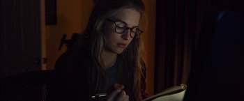 Movie still from “I Origins” (2014), directed by Mike Cahill – A woman with glasses is looking down at a book; Close Up shot, High angle