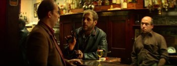 Movie still from “I Stand Alone” (1998), directed by Gaspar Noé – A man sitting at a table holding a cell phone; Medium shot, Over the shoulder angle