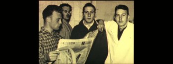 Movie still from “I Stand Alone” (1998), directed by Gaspar Noé – A group of men standing next to each other holding a newspaper; Medium shot, Low angle