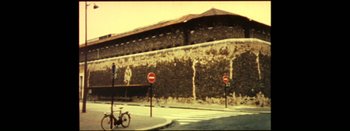 Movie still from “I Stand Alone” (1998), directed by Gaspar Noé – A bicycle parked on the side of the road near a building; Extreme Wide shot, Low angle