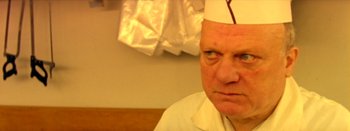 Movie still from “I Stand Alone” (1998), directed by Gaspar Noé – An older man wearing a paper chef's hat; Close Up shot, Over the shoulder angle