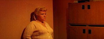 Movie still from “I Stand Alone” (1998), directed by Gaspar Noé – A woman standing in front of a mirror in front of a wall; Medium shot, High angle
