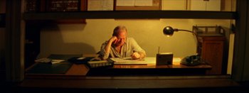 Movie still from “I Stand Alone” (1998), directed by Gaspar Noé – An older man sitting at a desk writing; Medium shot, High angle