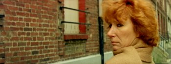 Movie still from “I Stand Alone” (1998), directed by Gaspar Noé – A woman with red hair standing in front of a brick building; Close Up shot, Low angle