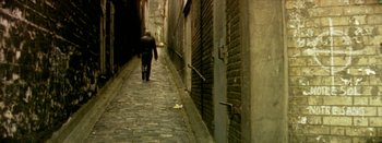 Movie still from “I Stand Alone” (1998), directed by Gaspar Noé – A man walking down a street in a dark alley way; Extreme Wide shot, High angle