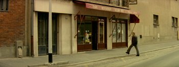 Movie still from “I Stand Alone” (1998), directed by Gaspar Noé – A building that has a restaurant on the side of the street; Extreme Wide shot, High angle