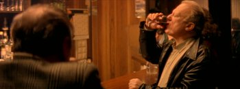 Movie still from “I Stand Alone” (1998), directed by Gaspar Noé – A man sitting at a table with a drink in front of him; Medium shot, Over the shoulder angle