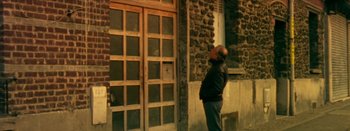 Movie still from “I Stand Alone” (1998), directed by Gaspar Noé – A man standing in front of an old building; Wide shot, Low angle