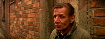 Movie still from “I Stand Alone” (1998), directed by Gaspar Noé – An older man is standing in front of a brick wall; Close Up shot, Low angle
