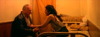 Movie still from “I Stand Alone” (1998), directed by Gaspar Noé – A woman sitting on a chair holding a man's hand; Medium shot, High angle