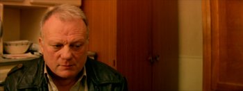 Movie still from “I Stand Alone” (1998), directed by Gaspar Noé – An older man wearing a leather jacket in front of wooden cabinets; Close Up shot, High angle