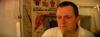 Movie still from “I Stand Alone” (1998), directed by Gaspar Noé – A man in a white shirt is in front of a poster; Close Up shot, Low angle
