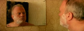 Movie still from “I Stand Alone” (1998), directed by Gaspar Noé – A person is looking in a mirror in a room; Extreme Close Up shot, Over the shoulder angle