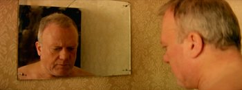 Movie still from “I Stand Alone” (1998), directed by Gaspar Noé – A woman looking in the mirror in front of a mirror; Close Up shot, Over the shoulder angle