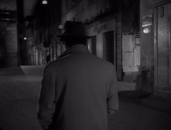Movie still from “I Vitelloni” (1953), directed by Federico Fellini – A man wearing a hat walking down a street; Medium shot, Over the shoulder angle