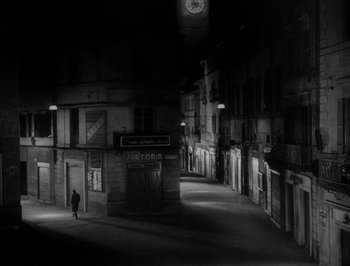 Movie still from “I Vitelloni” (1953), directed by Federico Fellini – A black and white photo of a person walking down a street; Extreme Wide shot, High angle