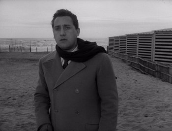 Movie still from “I Vitelloni” (1953), directed by Federico Fellini – A black and white photo of a man on the beach; Medium shot, Low angle