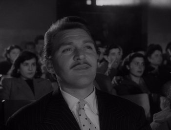 Movie still from “I Vitelloni” (1953), directed by Federico Fellini – A black and white photo of a man in a suit and tie; Close Up shot, Low angle