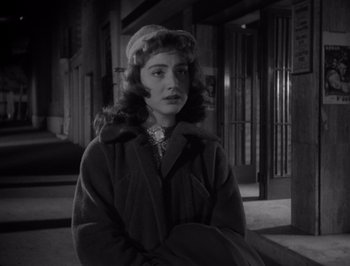 Movie still from “I Vitelloni” (1953), directed by Federico Fellini – A black and white photo of a woman in a coat and hat; Close Up shot, Over the shoulder angle