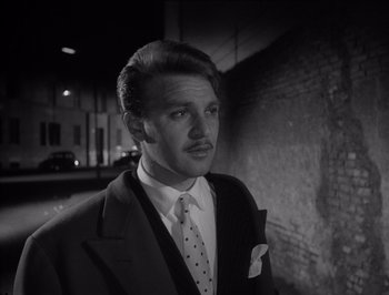 Movie still from “I Vitelloni” (1953), directed by Federico Fellini – A black and white photo of a man wearing a suit and tie; Close Up shot, Low angle