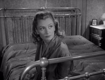 Movie still from “I Vitelloni” (1953), directed by Federico Fellini – An old black and white photo of a woman sitting on a bed; Medium shot, High angle