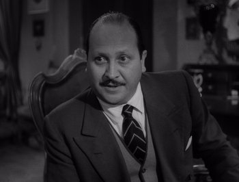 Movie still from “I Vitelloni” (1953), directed by Federico Fellini – A black and white photo of a man in a suit and tie; Close Up shot, Low angle