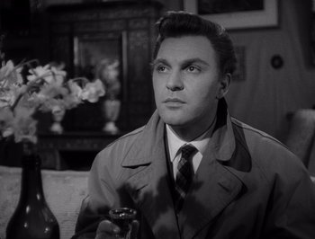 Movie still from “I Vitelloni” (1953), directed by Federico Fellini – A black and white photo of a man in a trench coat; Close Up shot, Low angle