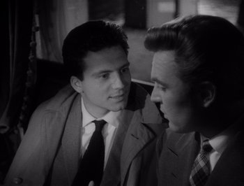 Movie still from “I Vitelloni” (1953), directed by Federico Fellini – Two men in suits talking to each other in a room; Close Up shot, Over the shoulder angle