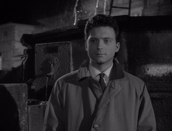 Movie still from “I Vitelloni” (1953), directed by Federico Fellini – A black and white photo of a man in a trench coat; Close Up shot, High angle