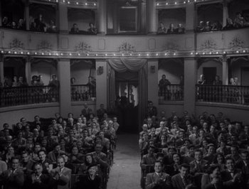 Movie still from “I Vitelloni” (1953), directed by Federico Fellini – An old photo of a crowd of people sitting in a theater; Extreme Wide shot, High angle
