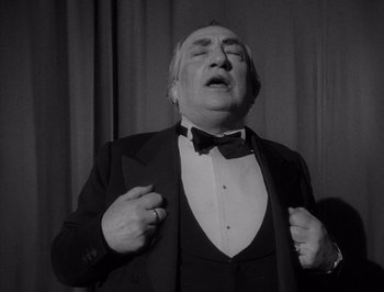 Movie still from “I Vitelloni” (1953), directed by Federico Fellini – An older man in a tuxedo singing into a microphone; Medium shot, Low angle