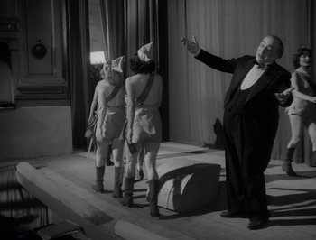 Movie still from “I Vitelloni” (1953), directed by Federico Fellini – A black and white photo of a man and two girls; Medium shot, Low angle